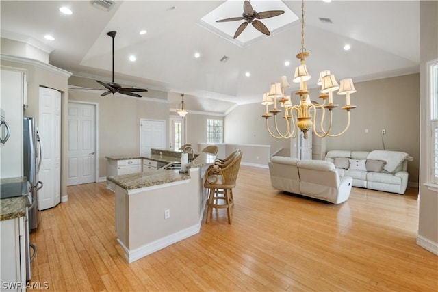 kitchen featuring hanging light fixtures, ceiling fan with notable chandelier, vaulted ceiling, and sink