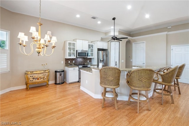 kitchen with appliances with stainless steel finishes, ceiling fan with notable chandelier, white cabinetry, decorative backsplash, and crown molding