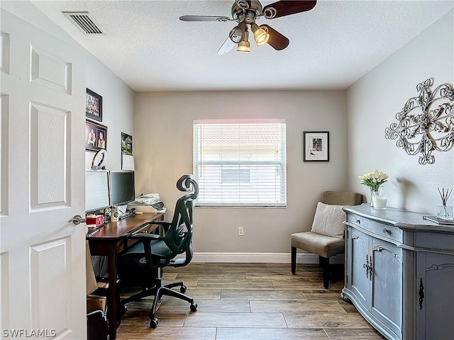 office with ceiling fan, light wood-type flooring, and a textured ceiling