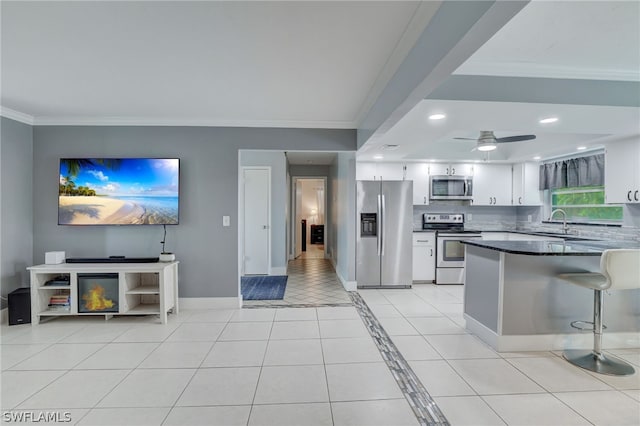 kitchen with crown molding, ceiling fan, light tile patterned floors, appliances with stainless steel finishes, and white cabinetry