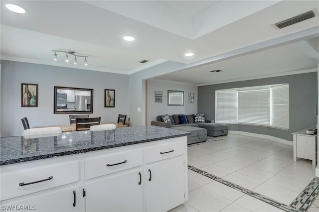 kitchen with light tile patterned flooring, white cabinets, dark stone counters, and ornamental molding