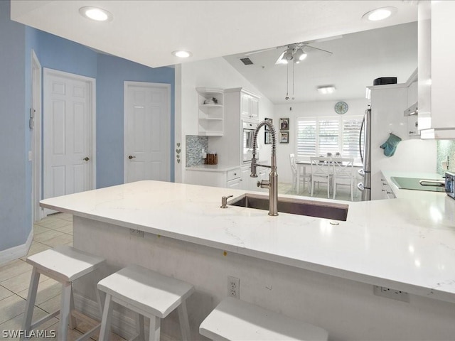 kitchen featuring white cabinetry, sink, a kitchen breakfast bar, and kitchen peninsula