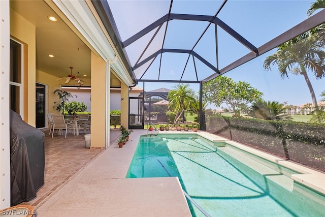 view of pool with glass enclosure, ceiling fan, and a patio area