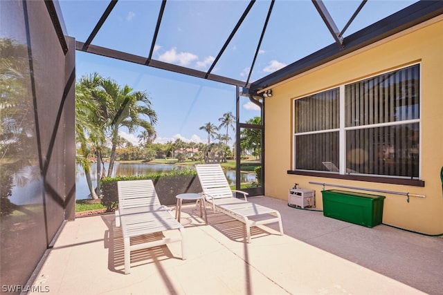 view of patio featuring glass enclosure and a water view