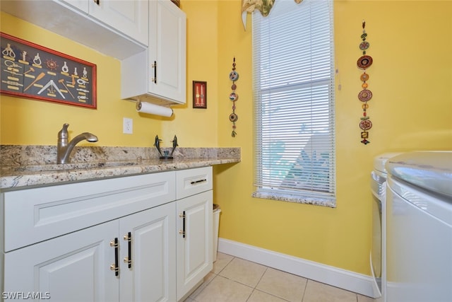 interior space with cabinets, washing machine and dryer, light tile patterned floors, and sink