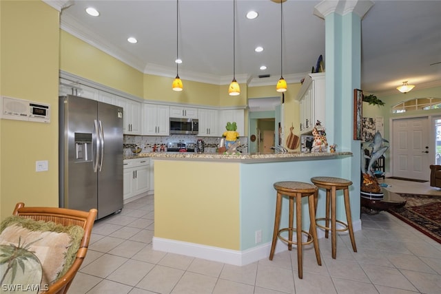 kitchen with kitchen peninsula, appliances with stainless steel finishes, light stone counters, white cabinetry, and hanging light fixtures