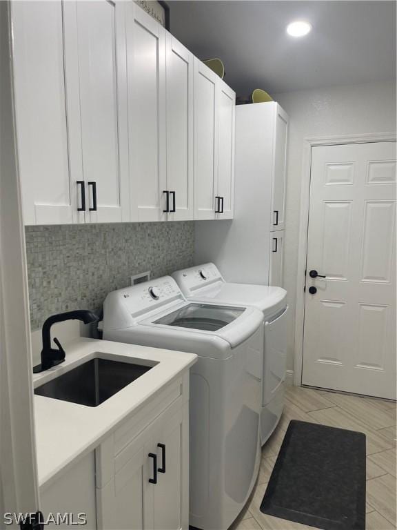 laundry area featuring cabinets, independent washer and dryer, and sink