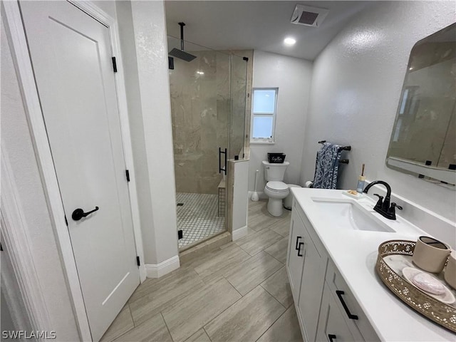 bathroom with toilet, a shower with shower door, and vanity