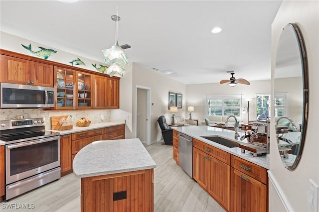 kitchen featuring hanging light fixtures, a center island with sink, appliances with stainless steel finishes, ceiling fan, and sink