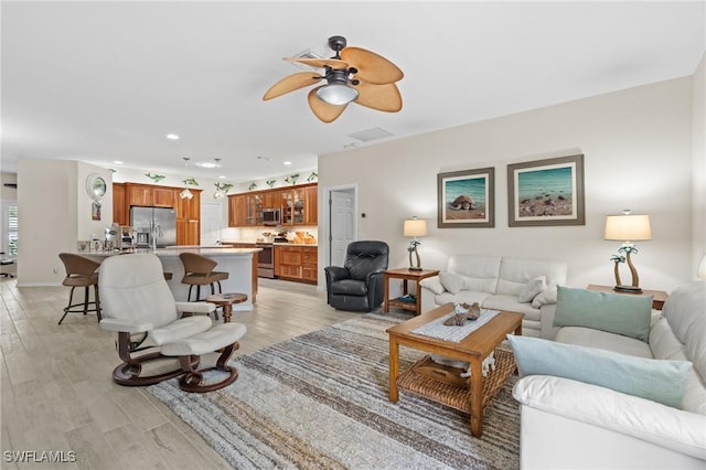 living room with ceiling fan and light hardwood / wood-style flooring