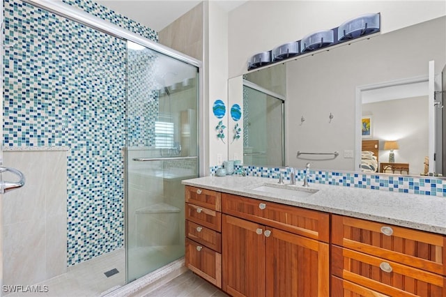 bathroom with a shower with shower door, backsplash, and vanity