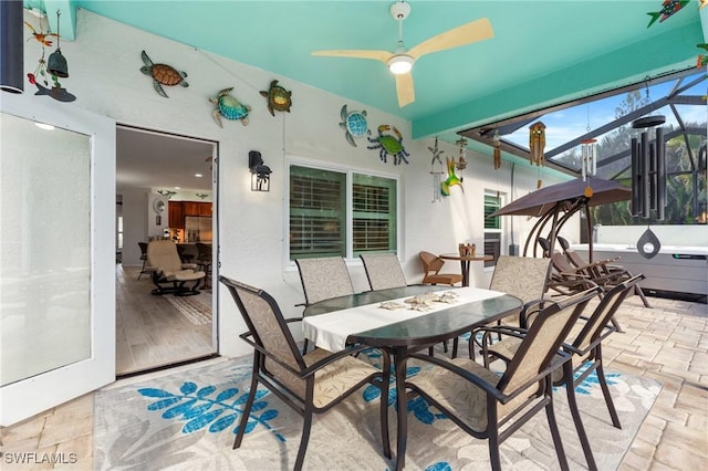 view of patio featuring ceiling fan and glass enclosure