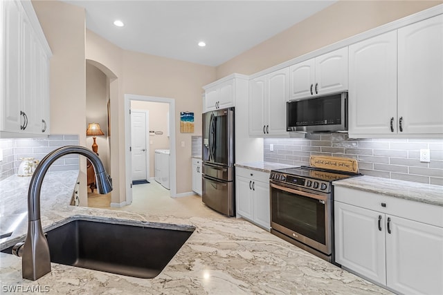 kitchen featuring white cabinets, sink, decorative backsplash, light stone countertops, and appliances with stainless steel finishes