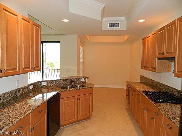 kitchen with dark stone counters, black appliances, a raised ceiling, sink, and ornamental molding