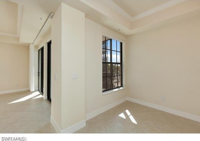 tiled spare room featuring a tray ceiling