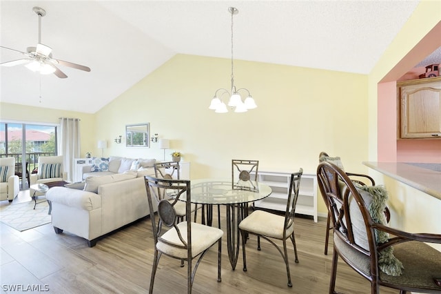 dining space with ceiling fan with notable chandelier, light hardwood / wood-style floors, and lofted ceiling