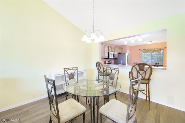 dining area featuring light hardwood / wood-style floors, an inviting chandelier, and lofted ceiling