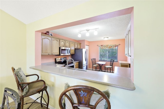 kitchen featuring kitchen peninsula, a breakfast bar, stainless steel appliances, and a textured ceiling