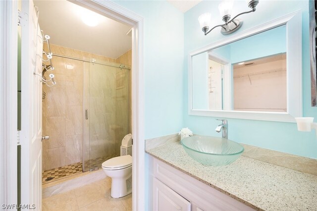 bathroom featuring tile patterned flooring, vanity, toilet, and a shower with shower door