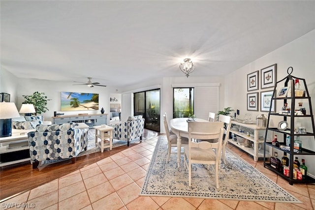 tiled dining area with ceiling fan with notable chandelier