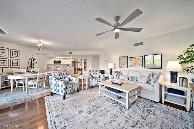 living room with hardwood / wood-style floors and ceiling fan with notable chandelier