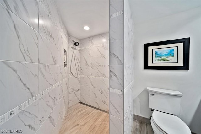 bathroom with a tile shower, toilet, and hardwood / wood-style flooring