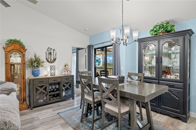 dining space with light wood-style flooring, a chandelier, and vaulted ceiling