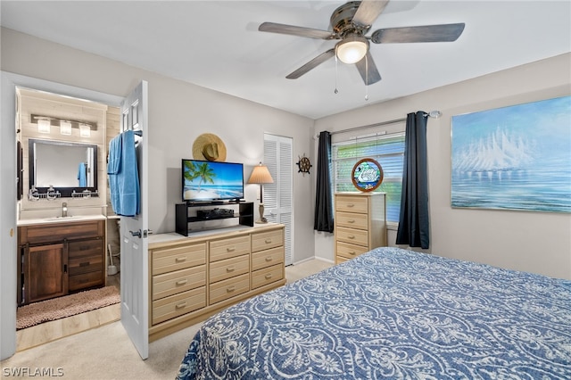 carpeted bedroom with connected bathroom, ceiling fan, a closet, and sink