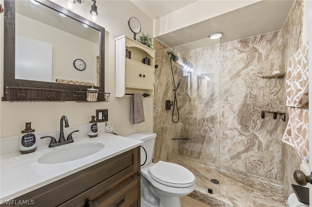 bathroom with a tile shower, vanity, and toilet