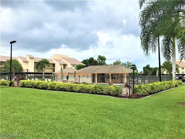 view of community with fence and a lawn