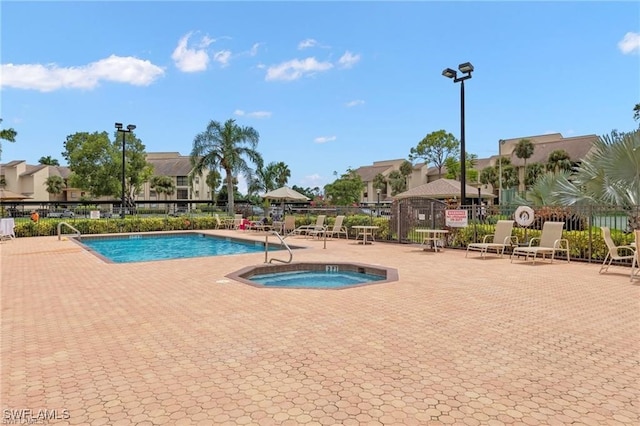 community pool with a patio area and fence