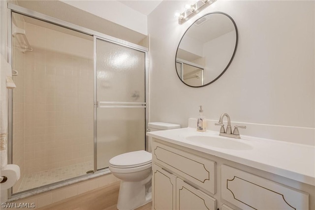 bathroom featuring toilet, vanity, wood-type flooring, and walk in shower