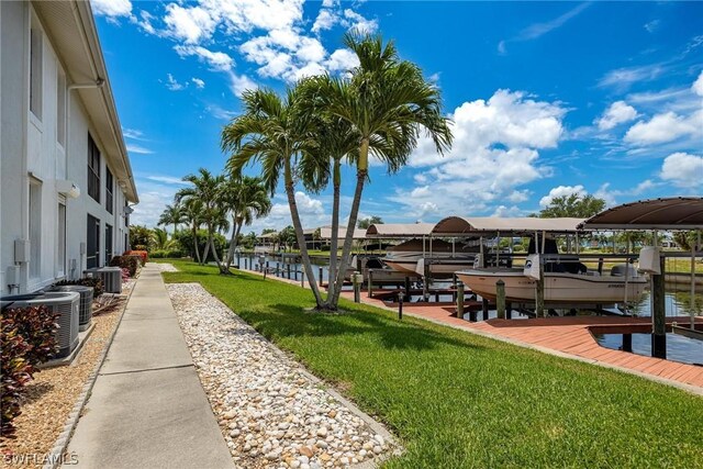 view of dock featuring central air condition unit, a lawn, and a water view