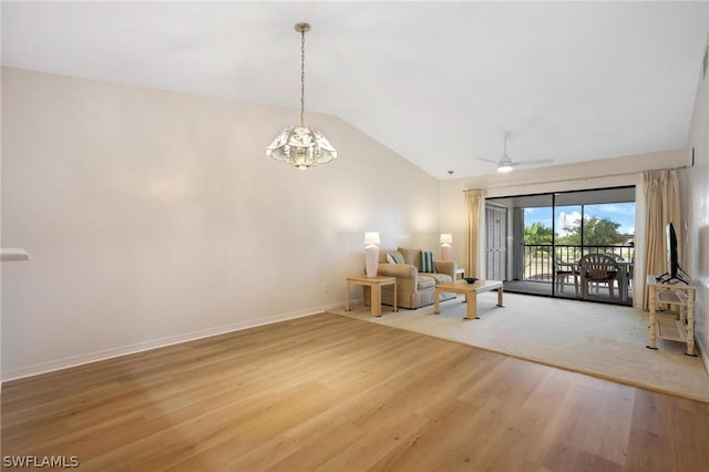 unfurnished living room with ceiling fan with notable chandelier, wood-type flooring, and vaulted ceiling