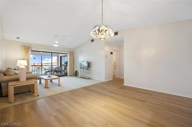 living room with hardwood / wood-style floors, ceiling fan with notable chandelier, and vaulted ceiling