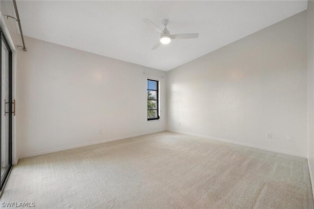 spare room featuring light carpet, vaulted ceiling, and ceiling fan