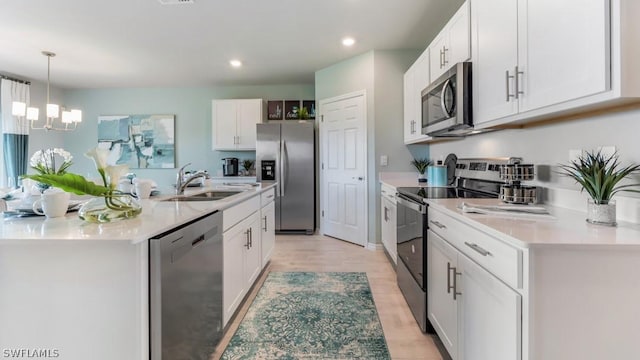 kitchen with pendant lighting, light countertops, appliances with stainless steel finishes, white cabinets, and a sink