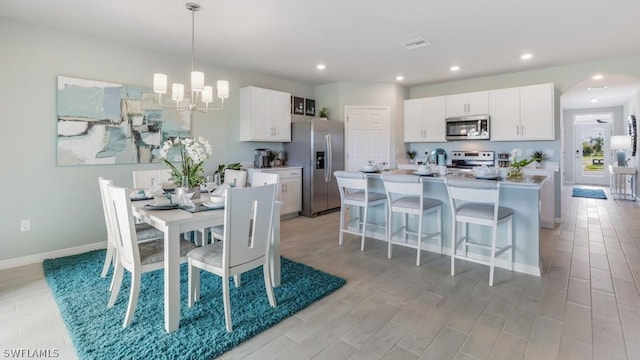 dining space with baseboards, visible vents, light wood-style floors, a chandelier, and recessed lighting