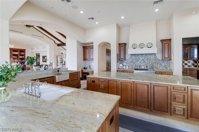 kitchen featuring a kitchen island, sink, light stone counters, and kitchen peninsula