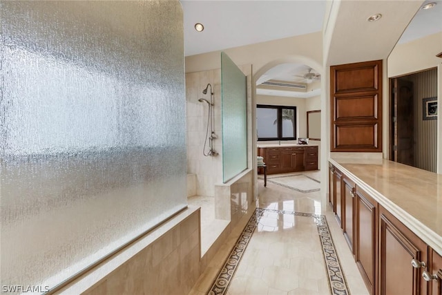 bathroom with ceiling fan, vanity, and a tile shower