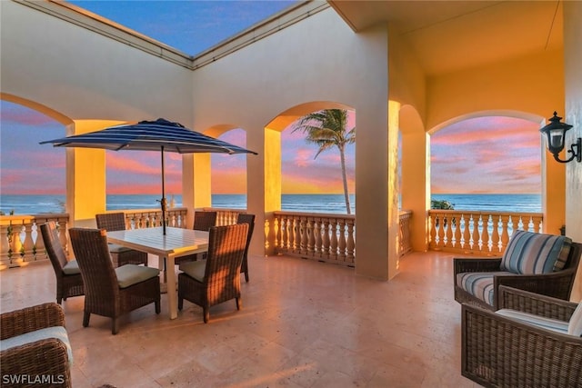 patio terrace at dusk with a beach view and a water view