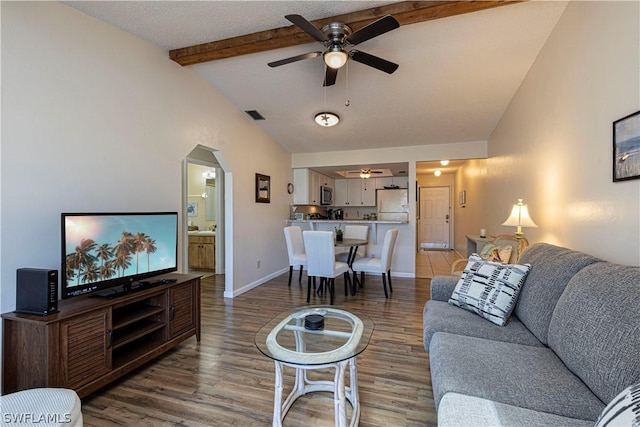 living room featuring hardwood / wood-style floors, vaulted ceiling with beams, and ceiling fan