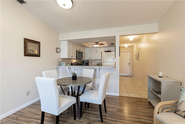 dining area with a textured ceiling, ceiling fan, and dark wood-type flooring