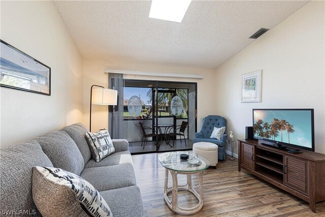 living room with lofted ceiling, a textured ceiling, and hardwood / wood-style flooring