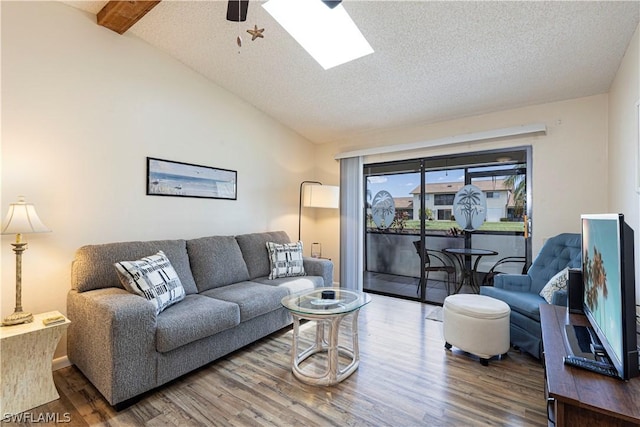 living room with lofted ceiling with skylight, ceiling fan, a textured ceiling, and hardwood / wood-style flooring