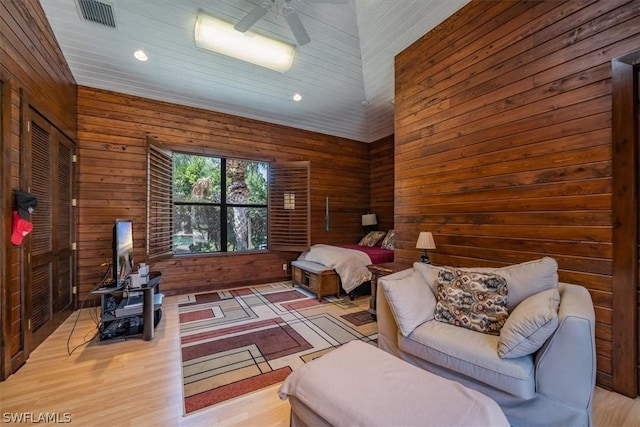 bedroom featuring wood-type flooring, wood walls, and ceiling fan