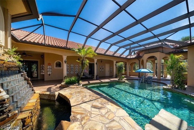 view of swimming pool featuring ceiling fan, pool water feature, glass enclosure, and a patio area