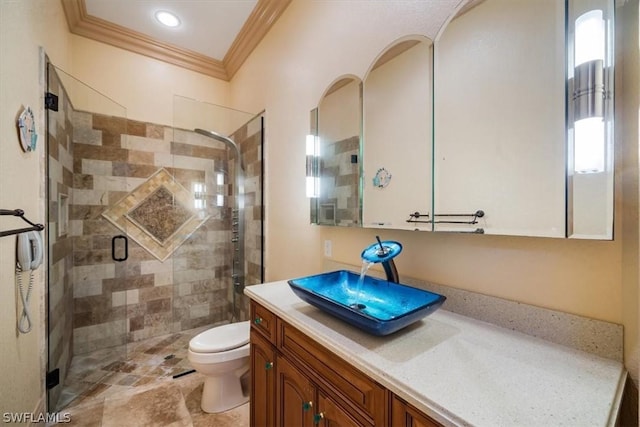 bathroom with toilet, vanity, a shower with shower door, and crown molding