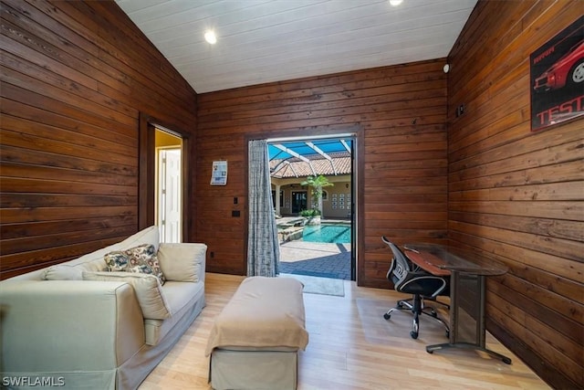 office area featuring lofted ceiling, wood walls, and light hardwood / wood-style flooring