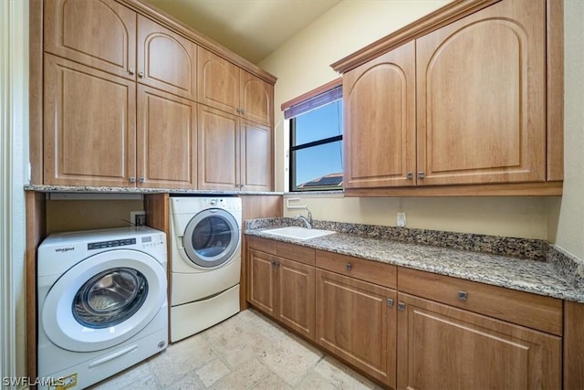 laundry area with washing machine and dryer, cabinets, and sink